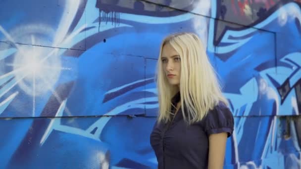 グラフィティと壁の背景にポーズをとる若いブロンドの女の子 ビデオセッション スローモーション — ストック動画