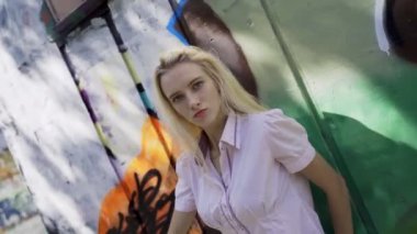 Genç sarışın kız grafitti ile bir duvar arka plan karşı poz. Video oturumu. yavaş çekim. Sallayarak kamera ile canlı çekim