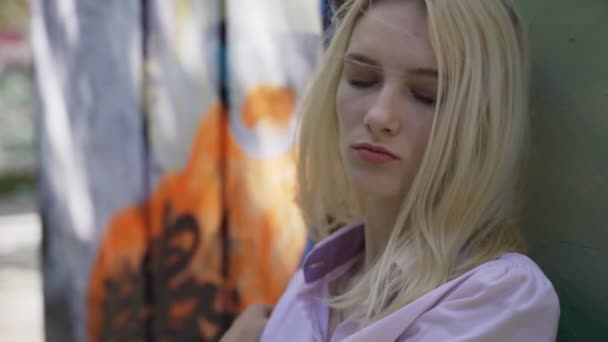 Junges Blondes Mädchen Posiert Vor Dem Hintergrund Einer Wand Mit — Stockvideo