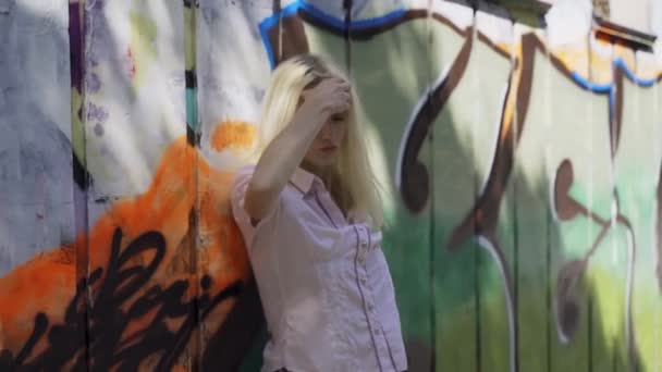 Jonge Blonde Meisje Poseren Tegen Een Achtergrond Van Een Muur — Stockvideo