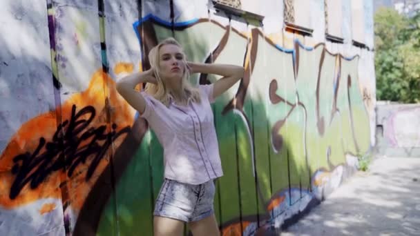 Menina Loira Posando Contra Fundo Uma Parede Com Grafitti Sessão — Vídeo de Stock