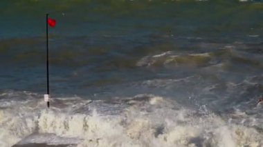 Güneşli havalarda denizde fırtına. Güçlü rüzgar. Yeşil-mavi deniz suyu, güçlü bir rüzgarda uçan martılar. Kırmızı bayrak uyarısı yüzmek yasaktır. 4k