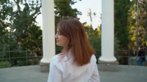 美少女クローズアップ 公園で白いシャツを着てカメラのポーズをとる少女 緑豊かな髪 — ストック動画