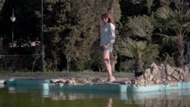 美少女クローズアップ 公園で白いシャツを着てカメラのポーズをとる少女 緑豊かな髪4K — ストック動画
