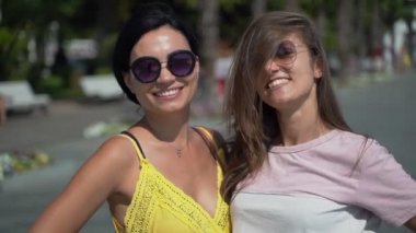 İki kız hava öpücüğü yolluyor. Güneşli bir yaz gününde güneş gözlüklü iki genç kız hava öpücüğü yolluyor.