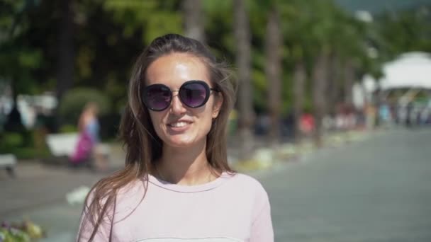 La fille envoie un baiser d'air. Belle jeune fille en lunettes de soleil se vêtir le sourire et envoie des embrassades d'air — Video