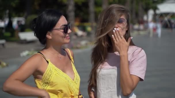 Duas menina envia um beijo de ar. Duas meninas bonitas jovens em óculos de sol em um dia ensolarado verão close-up enviar beijos de ar — Vídeo de Stock