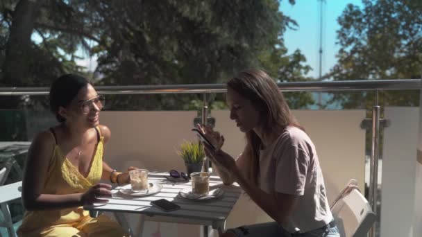 Две девушки в кафе разговаривают друг с другом — стоковое видео
