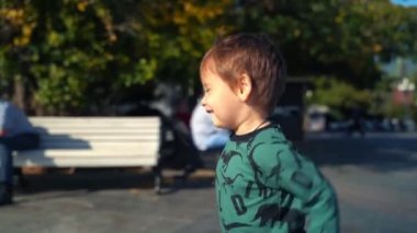 Küçük çocuk güneşli bir sonbahar gününde şehirde neşeyle koşar..
