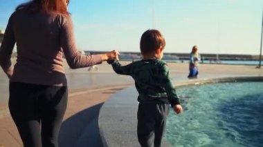 Genç bir anne ve oğlu şehirde çeşmenin etrafında dolaşıyorlar.