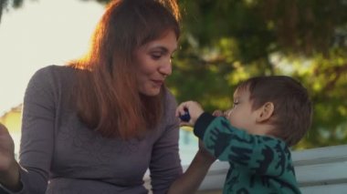 Anne ve oğlu dondurma yiyor. Anne ve çocuk. Dondurma yiyen çocuk. Annesi bankta oturan küçük bir çocuk dondurma yiyor ama çocuk annesiyle dondurma değiş tokuşu yapmak istiyor.