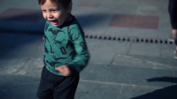 Kleine jongen loopt vrolijk in de stad op een zonnige herfstdag. — Stockvideo