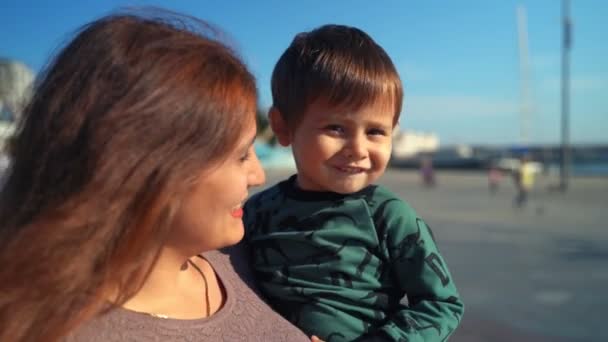 Eine junge Mutter und ihr Sohn laufen durch die Stadt — Stockvideo