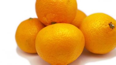 Beyaz arka planda beş mandalina dönüyor. Bir Mandarin diğerinin üzerinde yatar. Yakın plan.
