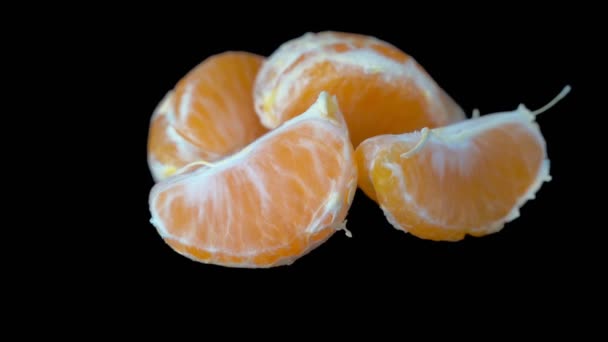 Fatias de tangerina descascada gira sobre um fundo preto. Close-up . — Vídeo de Stock