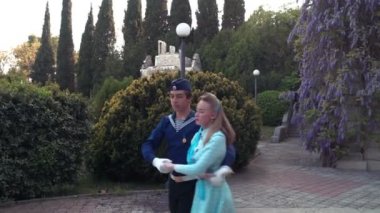Genç bir adam ve bir kız vals yapıyorlar. Bir öğrenci ve mavi elbiseli bir kız eski bir parkta dans ediyorlar. 4k