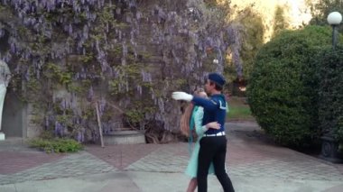Genç bir adam ve bir kız vals yapıyorlar. Bir öğrenci ve mavi elbiseli bir kız eski bir parkta dans ediyorlar. 4k