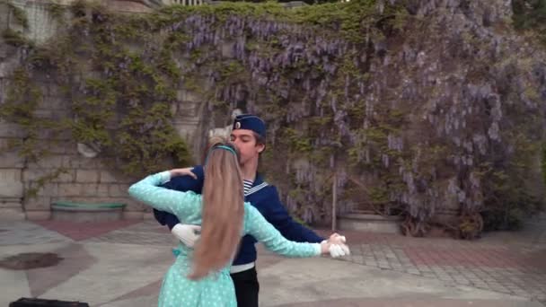 一个年轻人和一个女孩在跳华尔兹 一个学员和一个穿蓝色衣服的女孩在一个老公园里跳舞 — 图库视频影像