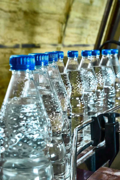 Pure drinking water plant. Work conveyor in the enterprise. Liter bottles on the conveyor are filled with water