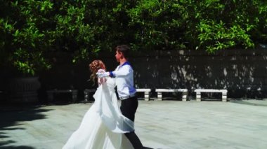 Genç bir adam ve bir kız vals yapıyorlar. Bir öğrenci ve beyaz balo elbisesi giymiş bir kız parkta dans ediyorlar. Yavaş çekimde vals dansı.