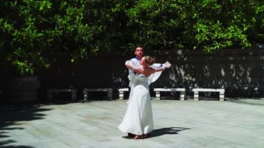 Genç bir adam ve bir kız vals yapıyorlar. Bir öğrenci ve beyaz balo elbisesi giymiş bir kız parkta dans ediyorlar. Yavaş çekimde vals dansı.