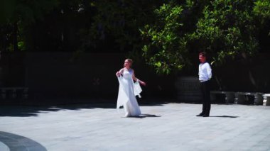Genç bir adam ve bir kız vals yapıyorlar. Bir öğrenci ve beyaz balo elbisesi giymiş bir kız parkta dans ediyorlar. Yavaş çekimde vals dansı.