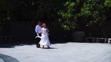 Genç bir adam ve bir kız vals yapıyorlar. Bir öğrenci ve beyaz balo elbisesi giymiş bir kız parkta dans ediyorlar. Yavaş çekimde vals dansı.