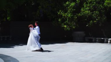 Genç bir adam ve bir kız vals yapıyorlar. Bir öğrenci ve beyaz balo elbisesi giymiş bir kız parkta dans ediyorlar. Yavaş çekimde vals dansı.