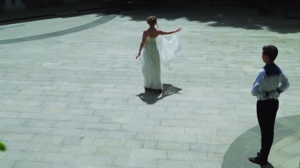 一个年轻人和一个女孩在跳华尔兹 一个学员和一个穿着白色舞会礼服的女孩在公园里跳舞 华尔兹慢动作舞 — 图库视频影像