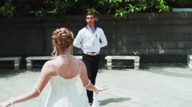 Genç bir adam ve bir kız vals yapıyorlar. Bir öğrenci ve beyaz balo elbisesi giymiş bir kız parkta dans ediyorlar. Yavaş çekimde vals dansı.
