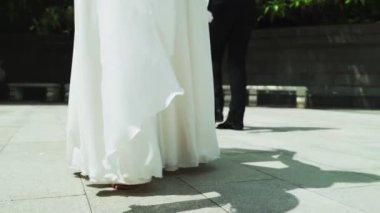 Dans eden bir erkek ve bir kızın bacakları. Üniformalı bir adam ve beyaz elbiseli bir kız parkta ağır çekimde vals yapıyorlar..