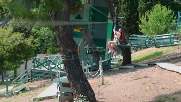 Des enfants dans le parc à cordes. Adolescente court un parcours d'obstacles dans un parc de corde. — Video