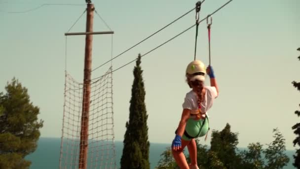 Kinderen in het touwenpark. Een klein meisje in een touwenpark met een snelheid trekt aan een bungee. — Stockvideo