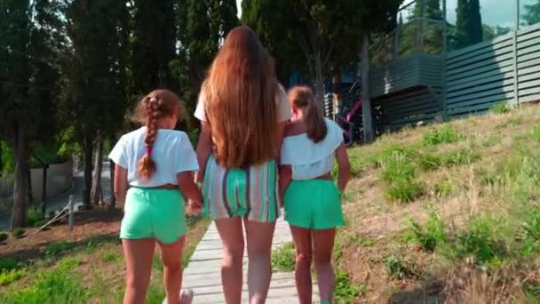 Children in the rope park. Three sisters walk together holding hands. — Stock Video