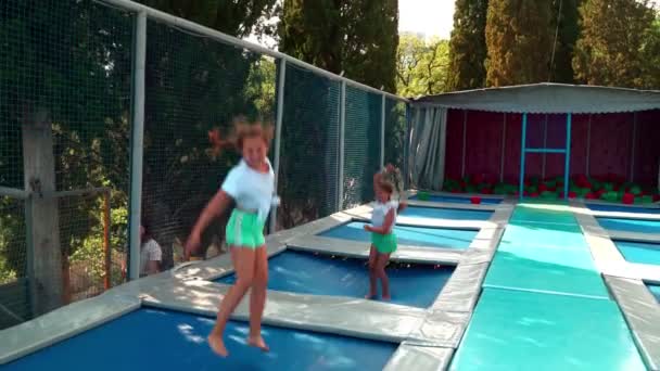 밧줄 공원에 있는 아이들. 세 자매는 즐겁게 트램펄린에서 뛰면서 웃고 탐닉한다. — 비디오