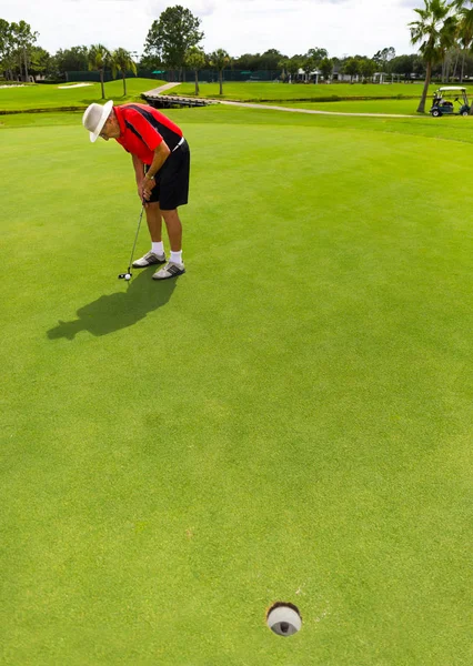 senior man putting  golf ball.