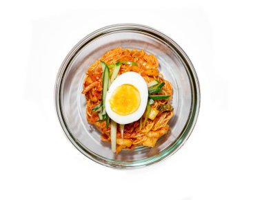 Bibim-guksu pişmiş şehriye, soya sosu, susam yağı, susam tohumu ve şekerle karıştırılmış susam yağında kızartılmış biftek, salatalık turşusu ve mantar içerir. Baharatlı eriştenin üstüne ve etrafına garnitürler konmuş.