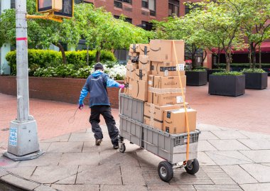 Manhattan, New York, ABD - 3 Nisan 2020: Amazon teslimatçısı, Coronavirus salgını sırasında 2. Cadde 'den kaldırıma paketler taşıyor.. 