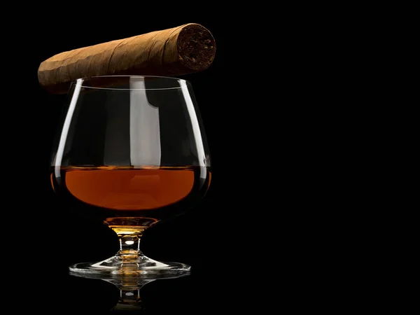 Cigar and cognac in a glass it is isolated on black