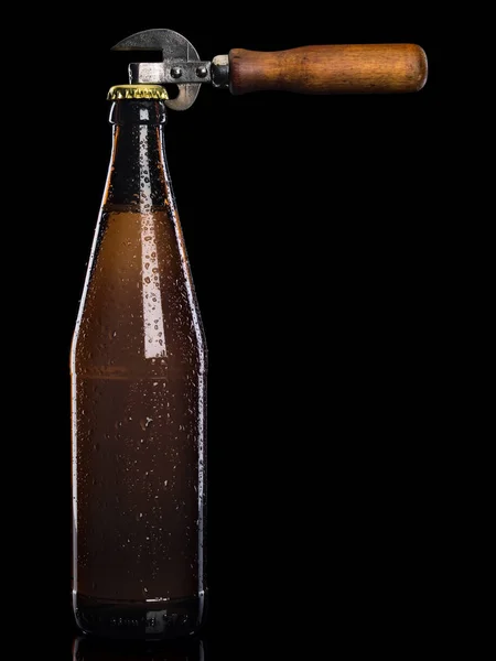 Can opener and beer in bottle from brown glass it is isolated on black