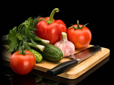 Group of vegetables: pepper, tomato, garlic, green onions, parsley, cucumber, santoku knife, wooden chopping board, it is isolated on black  clipart