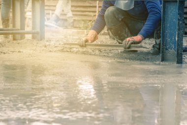 Adam oturmuş ve tahta bir spatula çimento için boşalırcasına hazır beton çelik takviye üzerinde sonra yolun karıştırılarak Mobil Beton Mikser yapmak kullanarak.