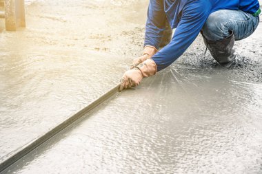 Adam oturmuş ve tahta bir spatula çimento için boşalırcasına hazır beton çelik takviye üzerinde sonra yolun karıştırılarak Mobil Beton Mikser yapmak kullanarak.