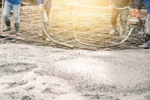 Workers man using a Vibration Machine for eliminate bubbles in concrete. after Pouring ready-mixed concrete on steel reinforcement to make the road by mixing mobile the concrete mixer.