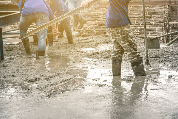 Workers man using a Vibration Machine for eliminate bubbles in concrete. after Pouring ready-mixed concrete on steel reinforcement to make the road by mixing mobile the concrete mixer.
