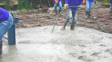 Adam Beton Mikser mobil karıştırma tarafından yol yapmak için çelik takviye hazır beton dökme sonra çimento için ahşap bir spatula kullanarak.