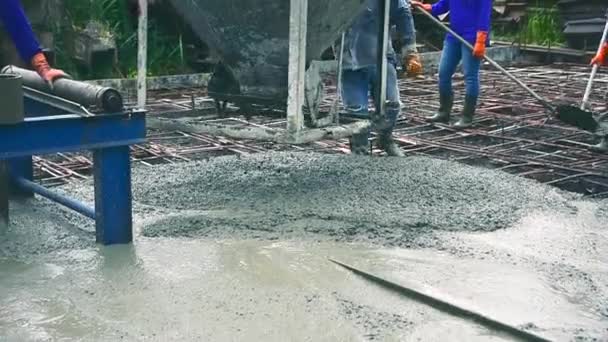携帯コンクリートミキサーを混合することにより 道路を作るために鋼の補強に準備混合コンクリートを注いだ後 セメントのための木製のスパチュラを使用して男 — ストック動画