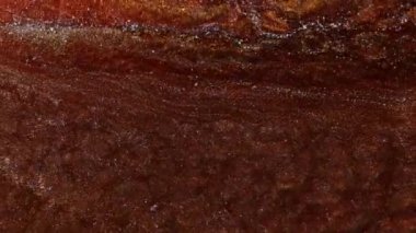 Bakır, demir ve pas renginde sıvı. Sudaki parlak pigmentler dalgalarda titreşir. Soyut bronz rengini nehrin rengine boyardı. Makro görüntüyü kapat. Mürekkep suyun altında dönüyor..