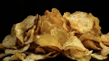 Tuzlu patates cipsi siyah arka plan üzerinde döndürme