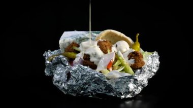 Taze falafel pide ekmek salata ve acı sos ile. Siyah arka plan üzerinde döndürme.